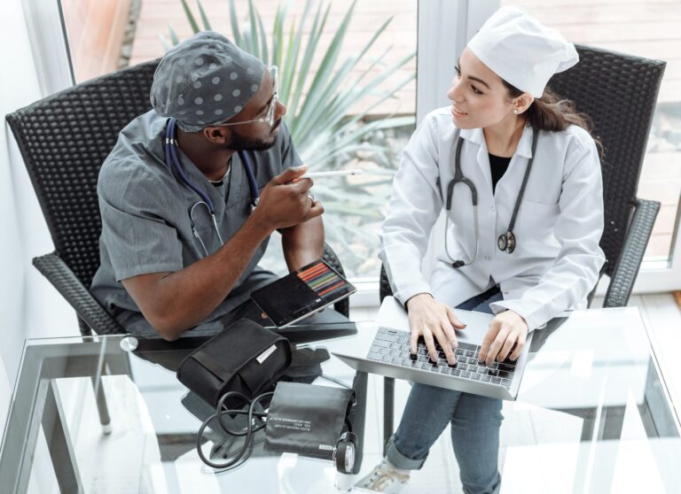 A doctor and patient are sitting in front of a laptop.