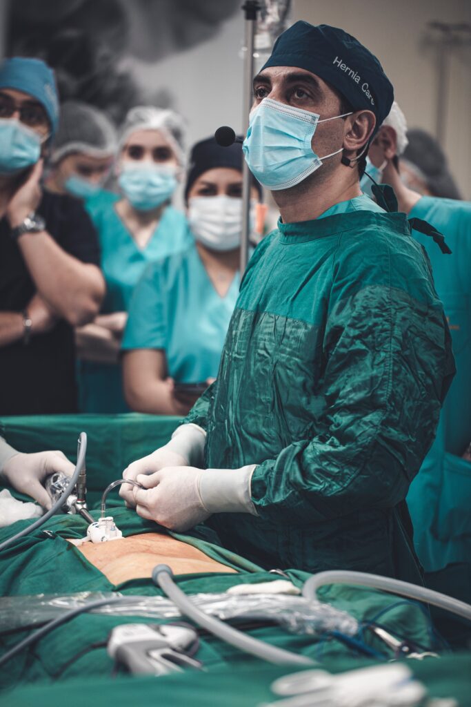 A surgeon is performing surgery on someone in the background.